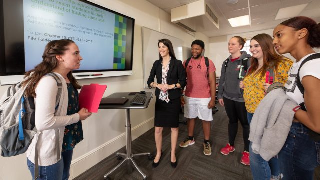 Female student speaking to professor and students