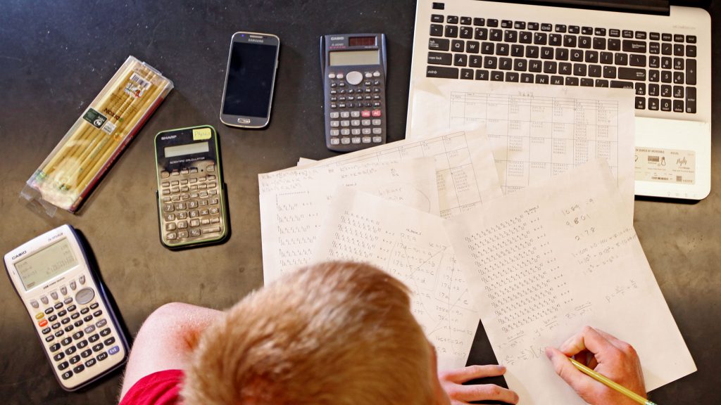 Student study formulas with calculators and laptop