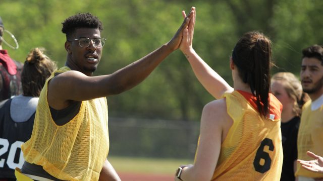 Male and female students high-fiving during flag football