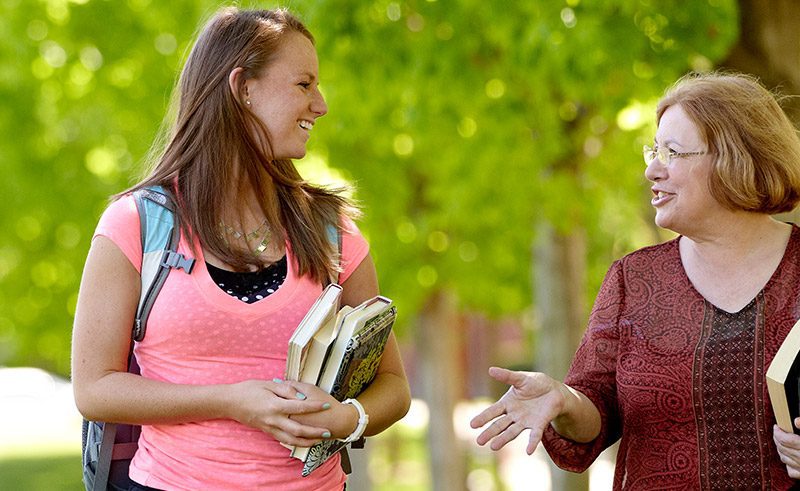 Female student talking to a female professor on the campus mall