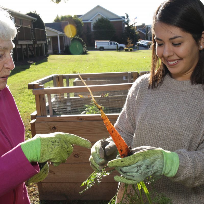 Female student gardening with older female