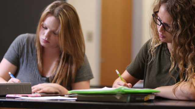 Two female students taking notes