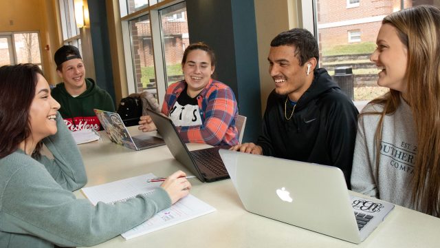Students studying and laughing around laptops