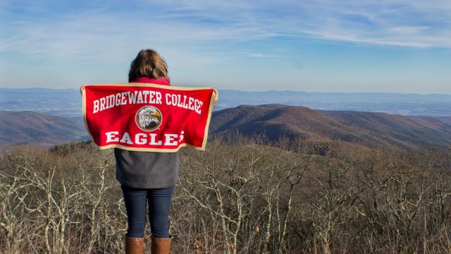 Student at Reddish Knob holding Bridgewater College flag