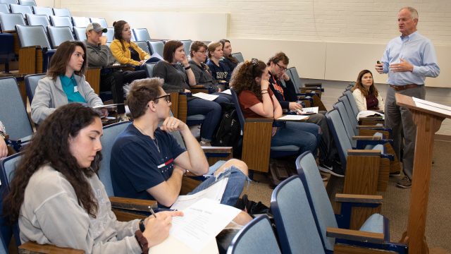 A guest lecturer talks to a Business class