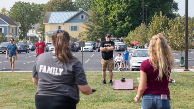 Students and families play cornhole on campus