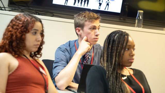 Three students listening in classroom.