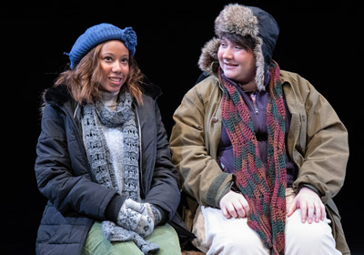 Two people dressed in winter clothing sit on a bench|two people dressed in winter clothing sit on a bench