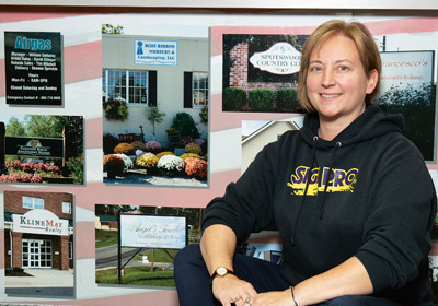 |Woman crouches down in front of wall covered in photos