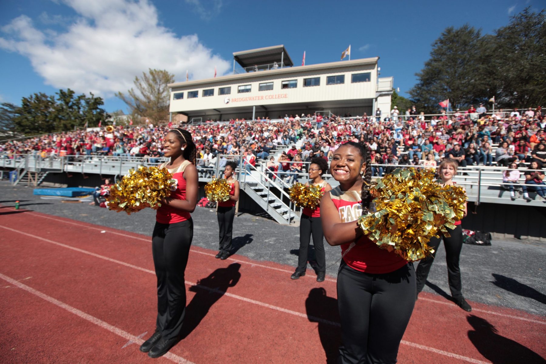 Cheerleaders stand in front of crowded stands