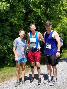 A woman and two man wearing running clothes stand next to each other