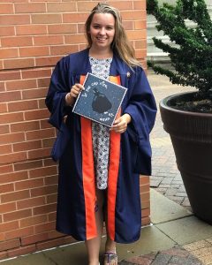 Woman in graduation robes holds diploma