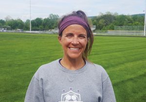 woman standing on soccer field|||Young woman kicks a soccer ball on a field