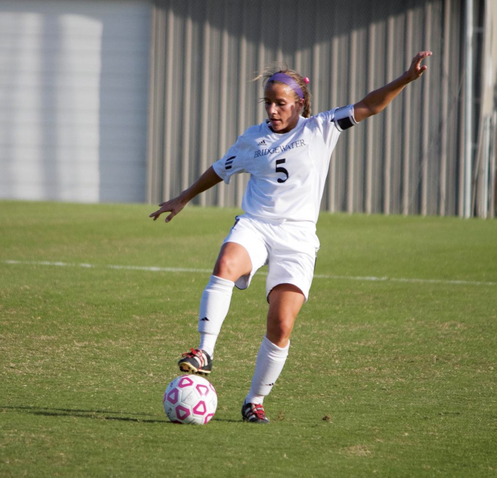 Young woman kicks a soccer ball on a field