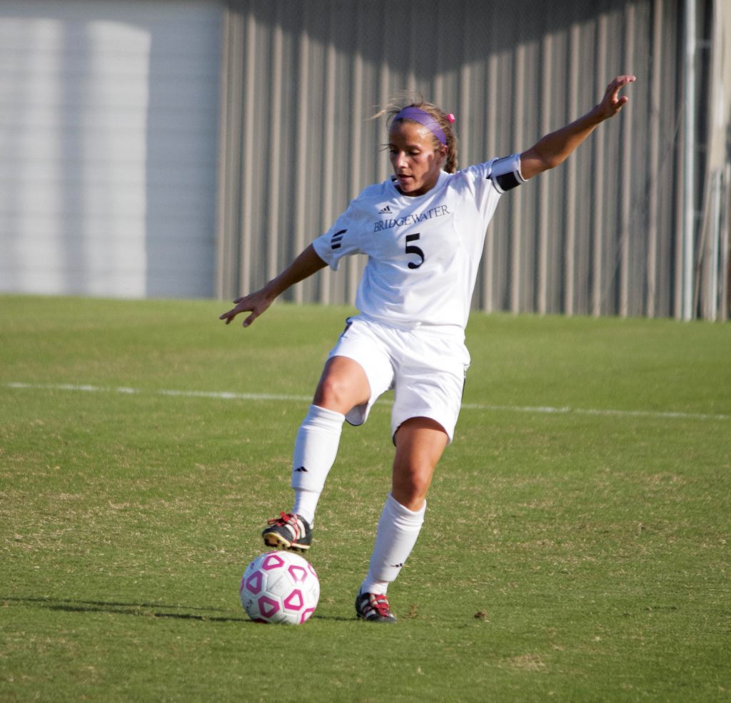 Young woman kicks a soccer ball on a field