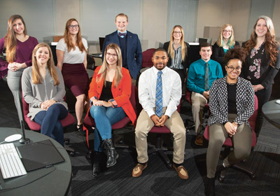 Students seated and standing smiling at the camera|Students seated and standing smiling at the camera|