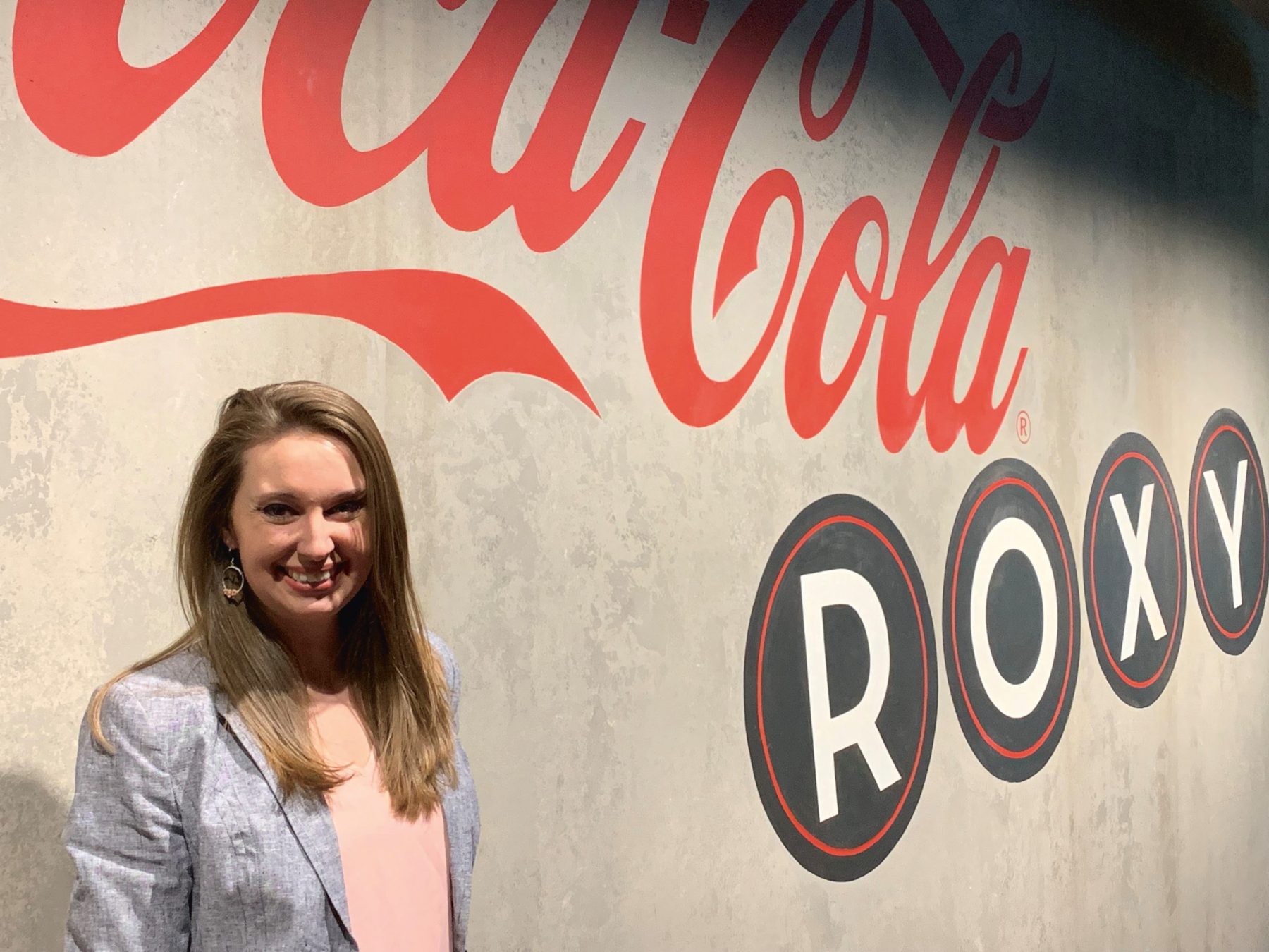 Young man stands next to a wall that says Coca-Cola Roxy