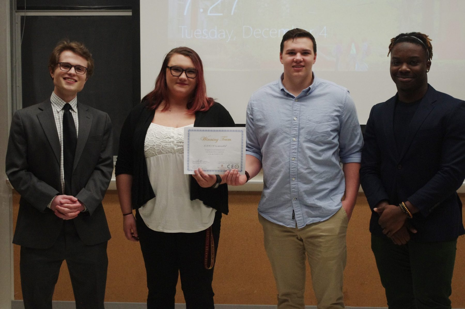 Three guys and one girl hold a piece of paper