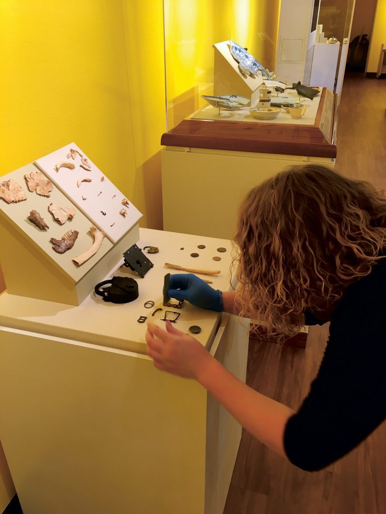 woman brushes artifacts on a display table