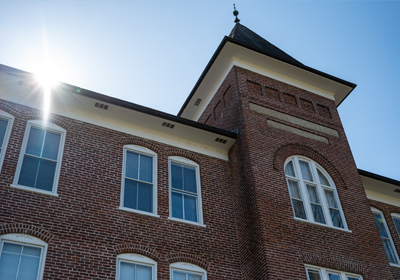 On-Campus brick building with sun peaking over the roofline