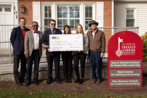 Four men and two women stand behind an over sized check