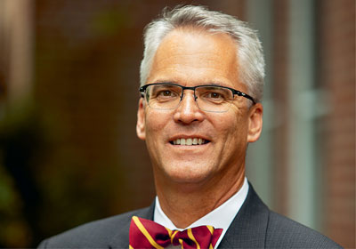 Man in bowtie and glasses smiles at camera