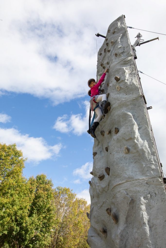 A young girl climbs up a rock wall