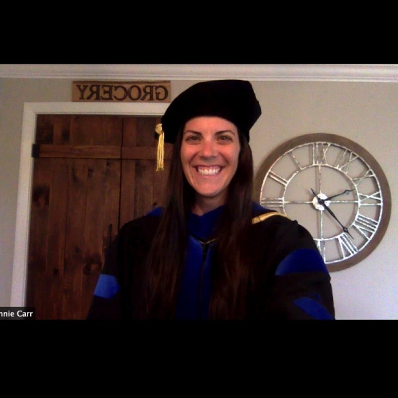 student in cap and gown in a computer screenshot with a professor in a cap and gown