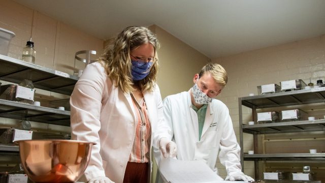 Female student and male professor were face masks while standing in a laboratory