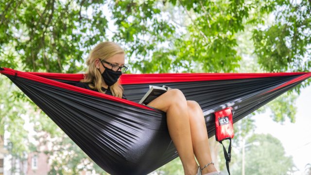 Female student sitting in hammock reading