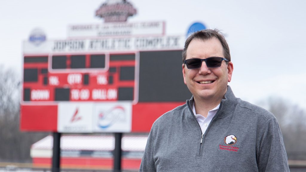 Headshot of Barry Flowe with stadium scoreboard blurred in the background