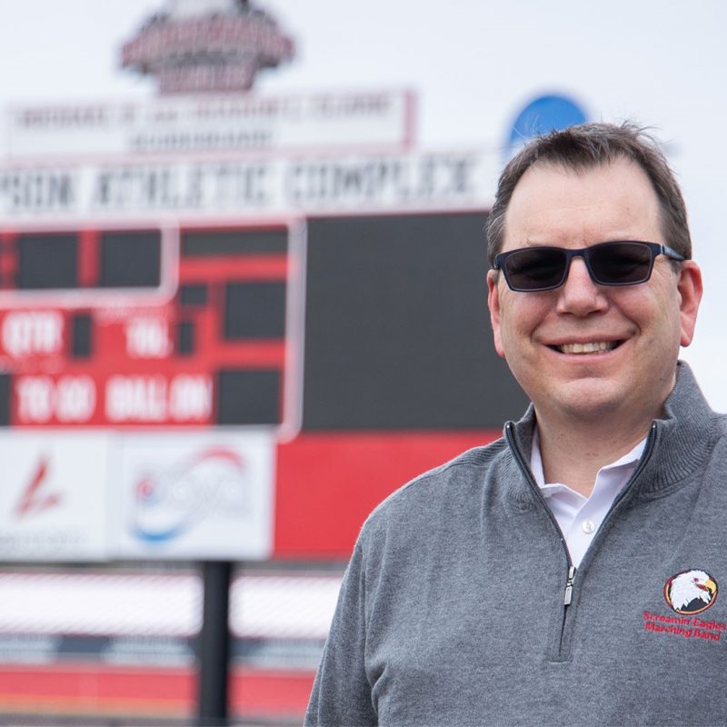 Headshot of Barry Flowe with stadium scoreboard blurred in the background