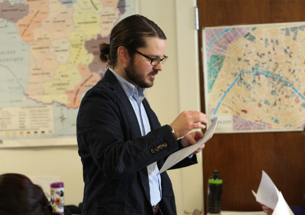 Professor in classroom with maps in the background