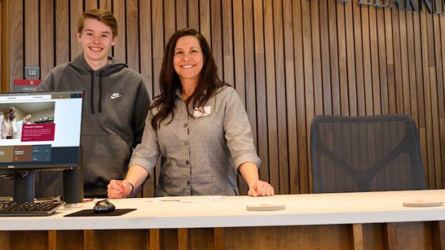 Man and woman standing at a desk smiling for a photo