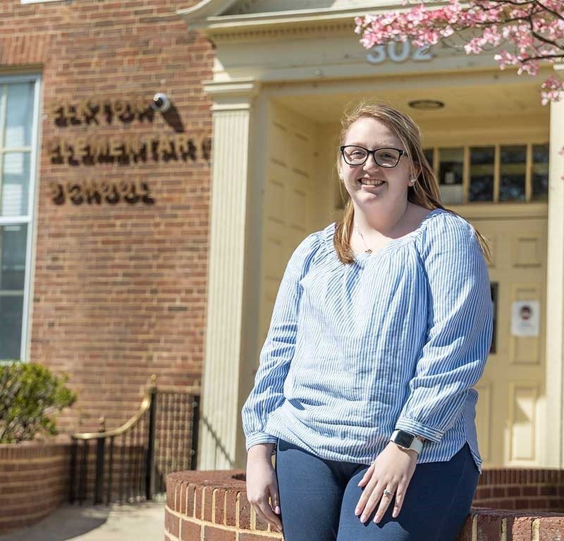 Female pictured in front of brick building