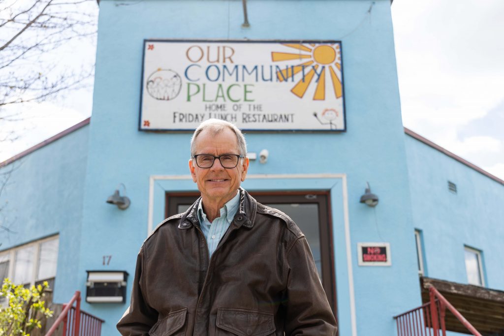 Laurie Miller posing in front of Our Community Place building