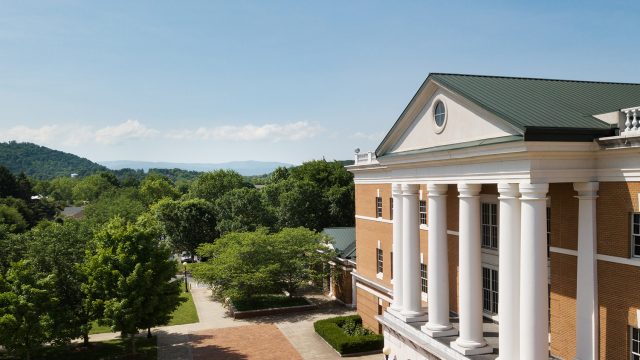 Aerial shot of McKinney with blue skies, green trees, and mountain the background