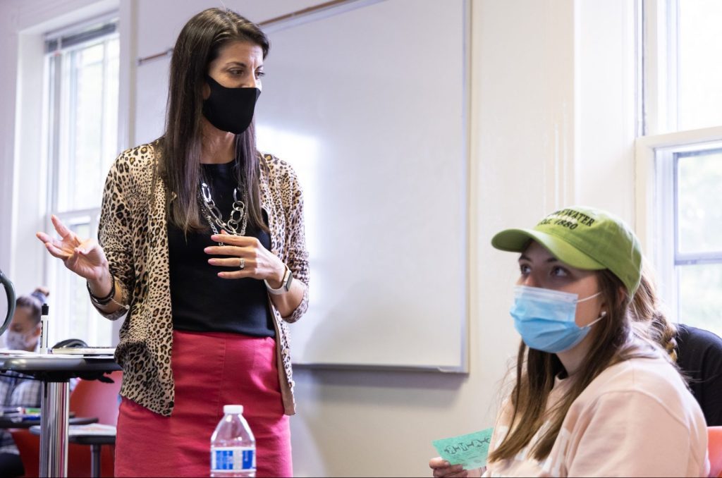 Professor Jennie Carr stands in a classroom teaching students who can be seen in the foreground of the photo