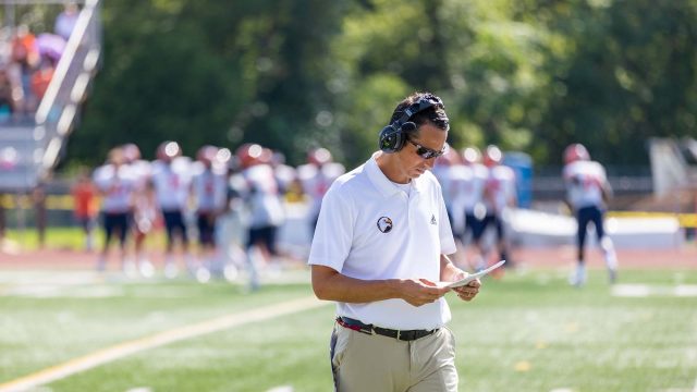 Coach Scott Lemn looking at playbook at football game