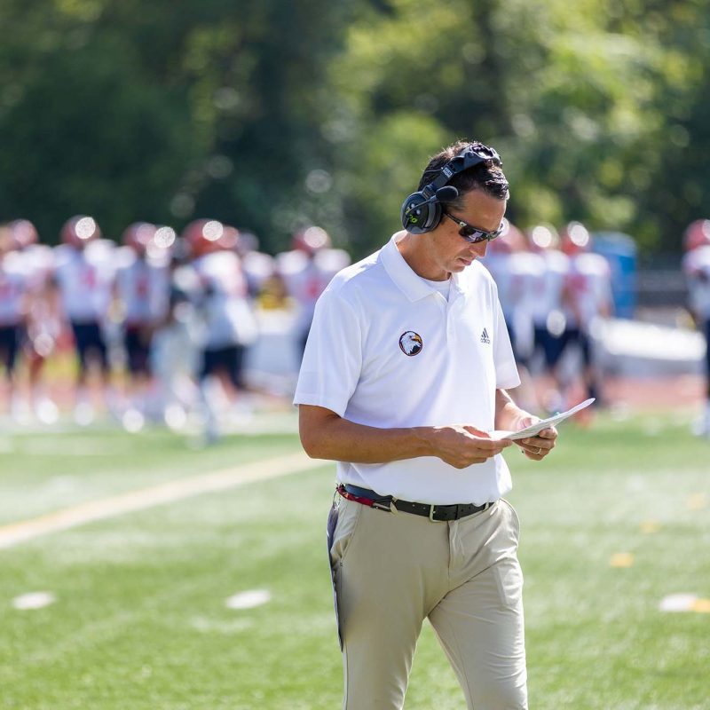 Coach Scott Lemn looking at playbook at football game