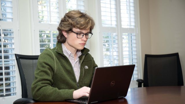 Michael Caldwell sitting down looking at Dell laptop