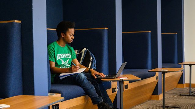 Student sitting in booth working on a laptop