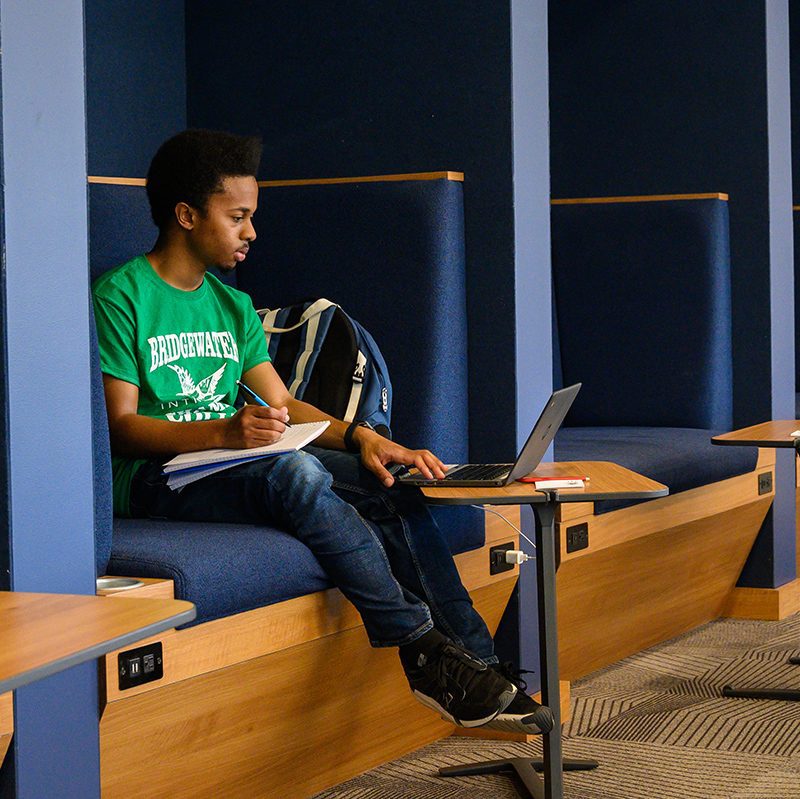 Student sitting in booth working on a laptop