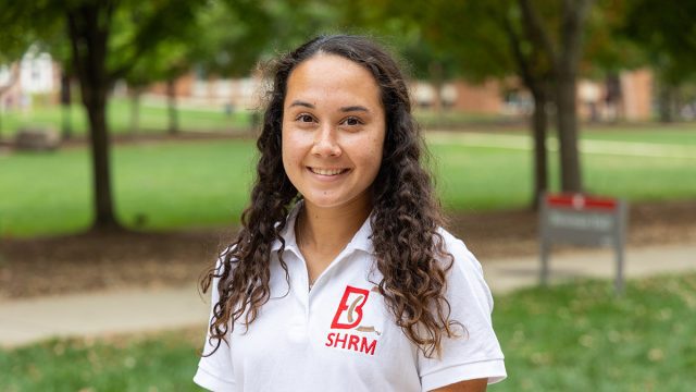 Woman smiling wearing B-C S-H-R-M polo