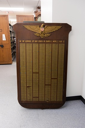 A large wooden board with a gold Eagle on top and the words "In Service of our country during World War II." A list of names is shown underneath