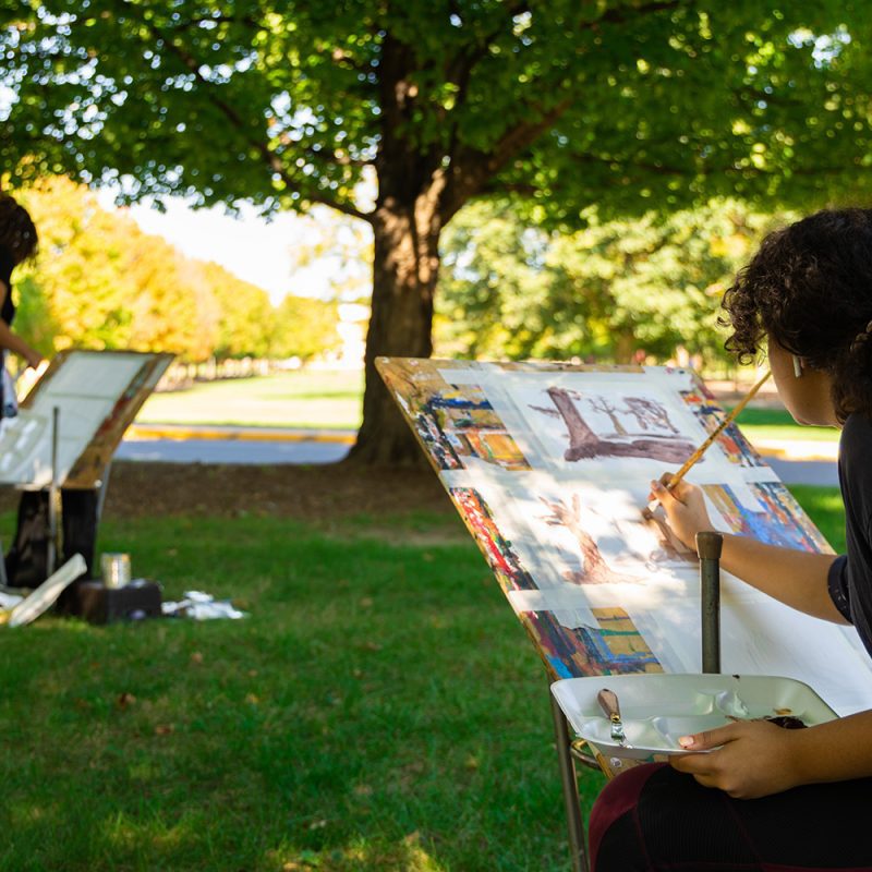 Two students painting artwork outside