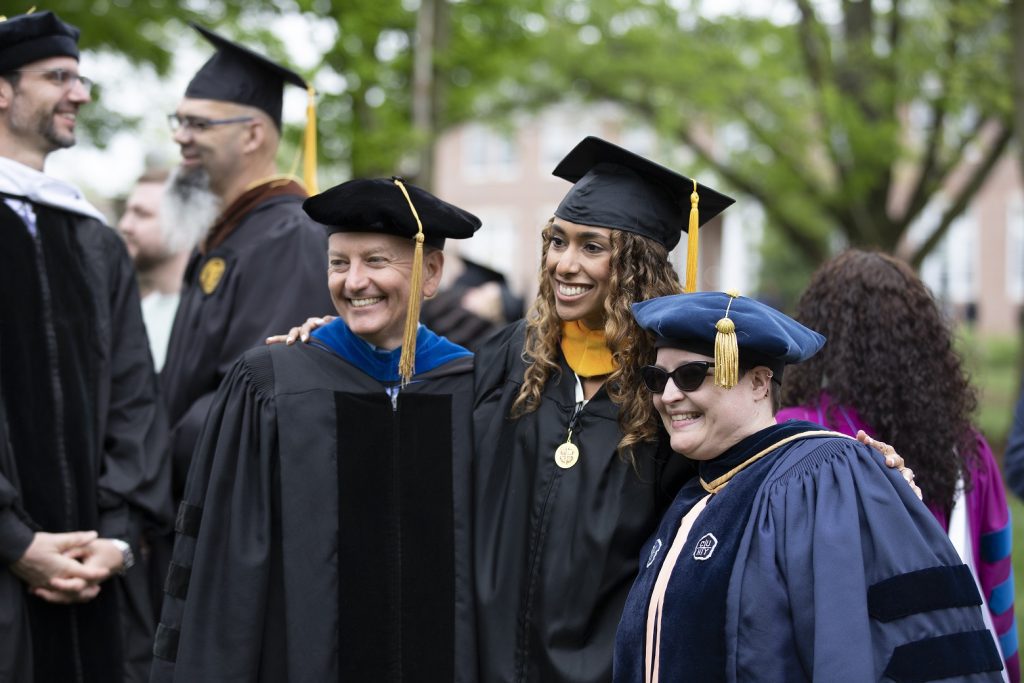 Female student poses for photo with two professors