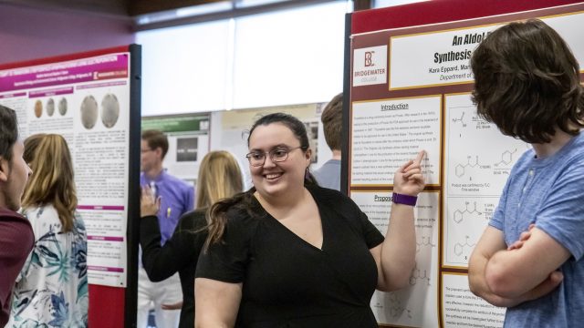 Student in black shirt pointing to project board