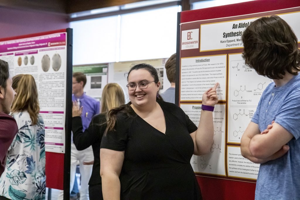 Student in black shirt pointing to project board