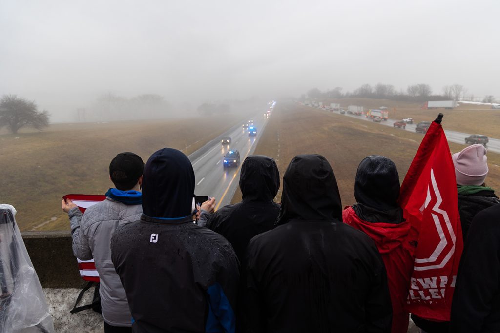 Bridgewater College students stand at an overpass on I-81 as the police processional drives by